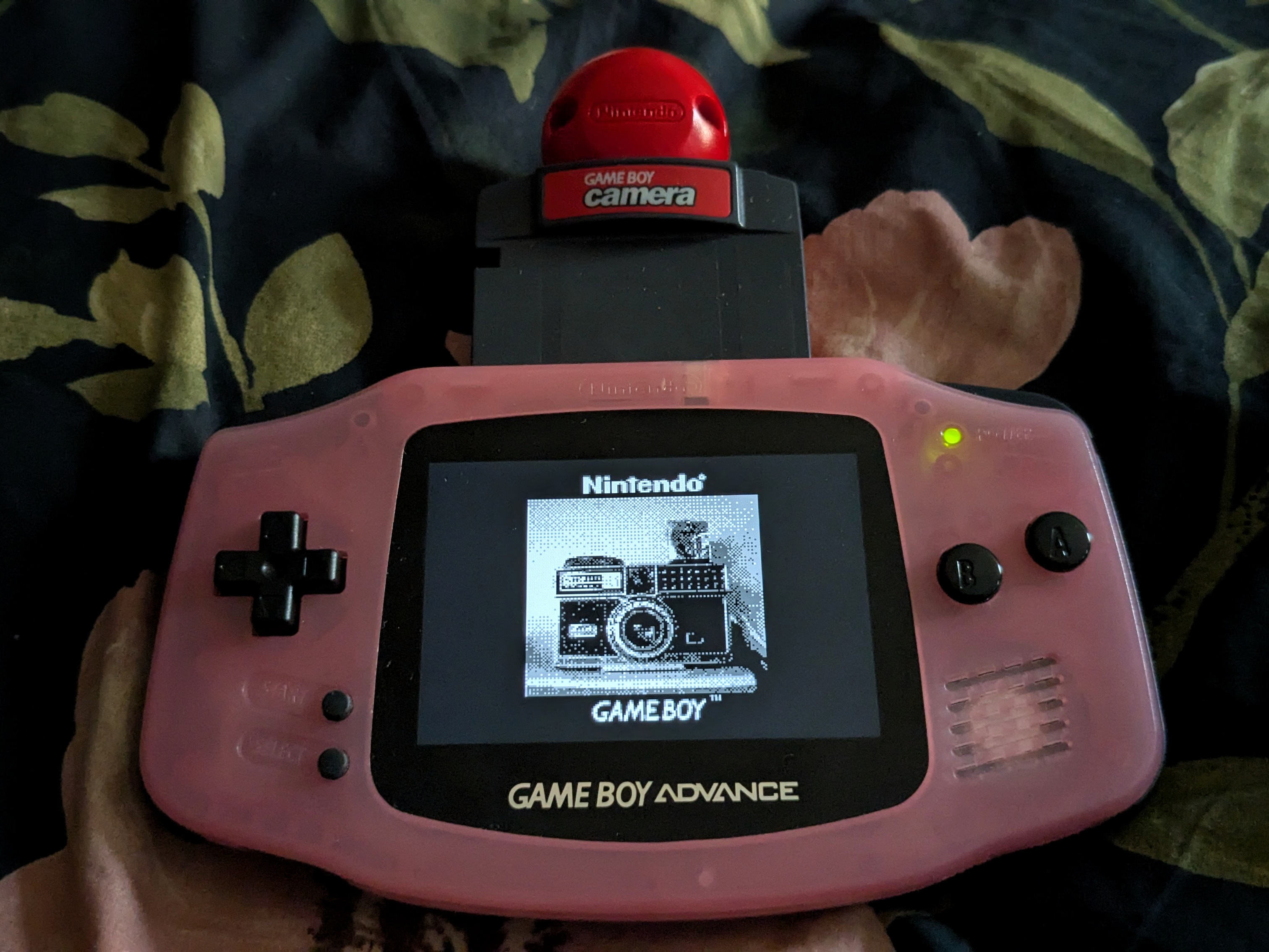 a light pink, slightly transluscent Game Boy Advance modded with a brightly lit, clear looking screen