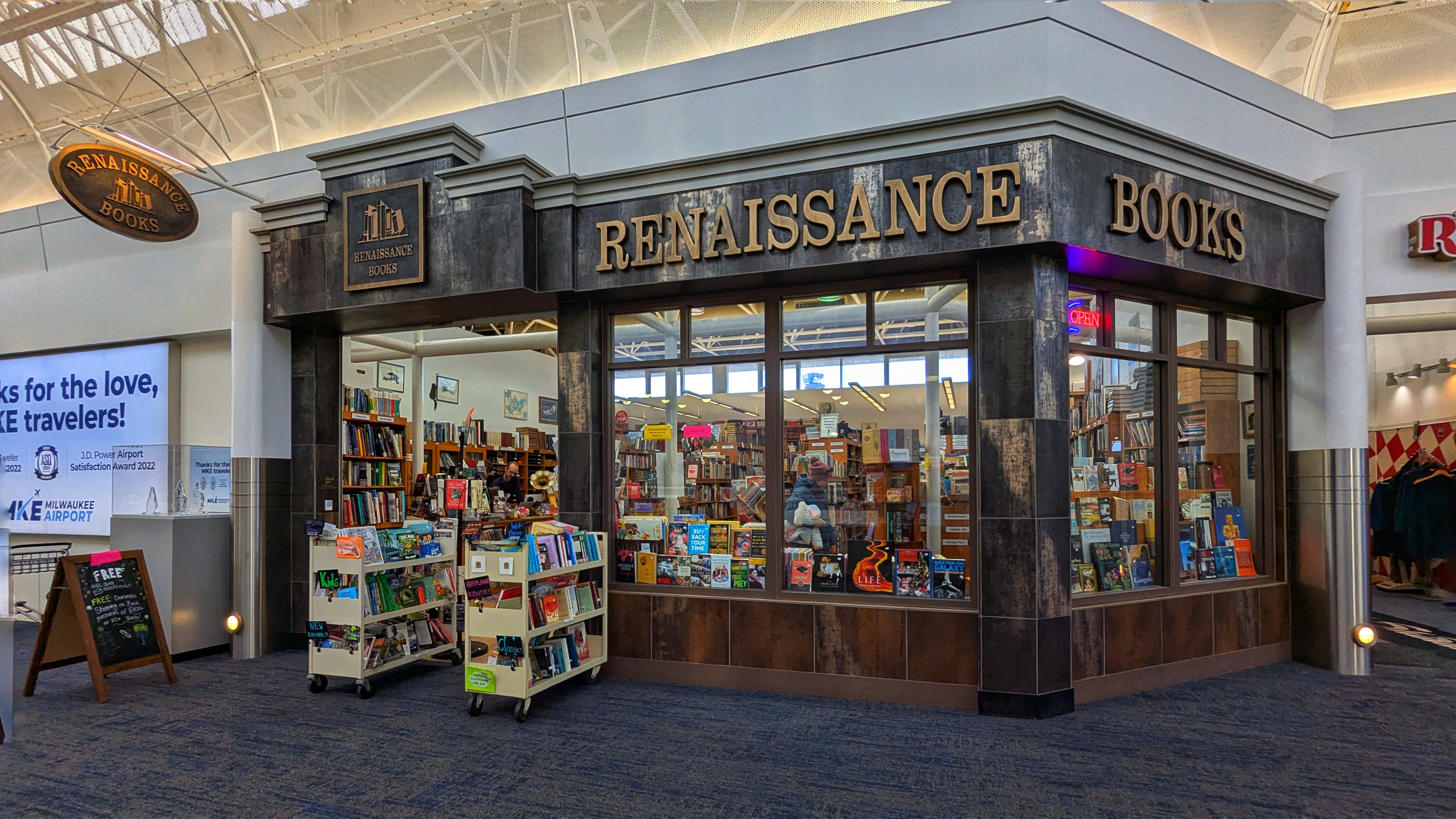 a photo of a used bookstore, located inside of an airport terminal.